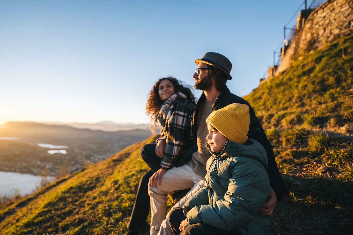 family sitting on a hilltop at sundown