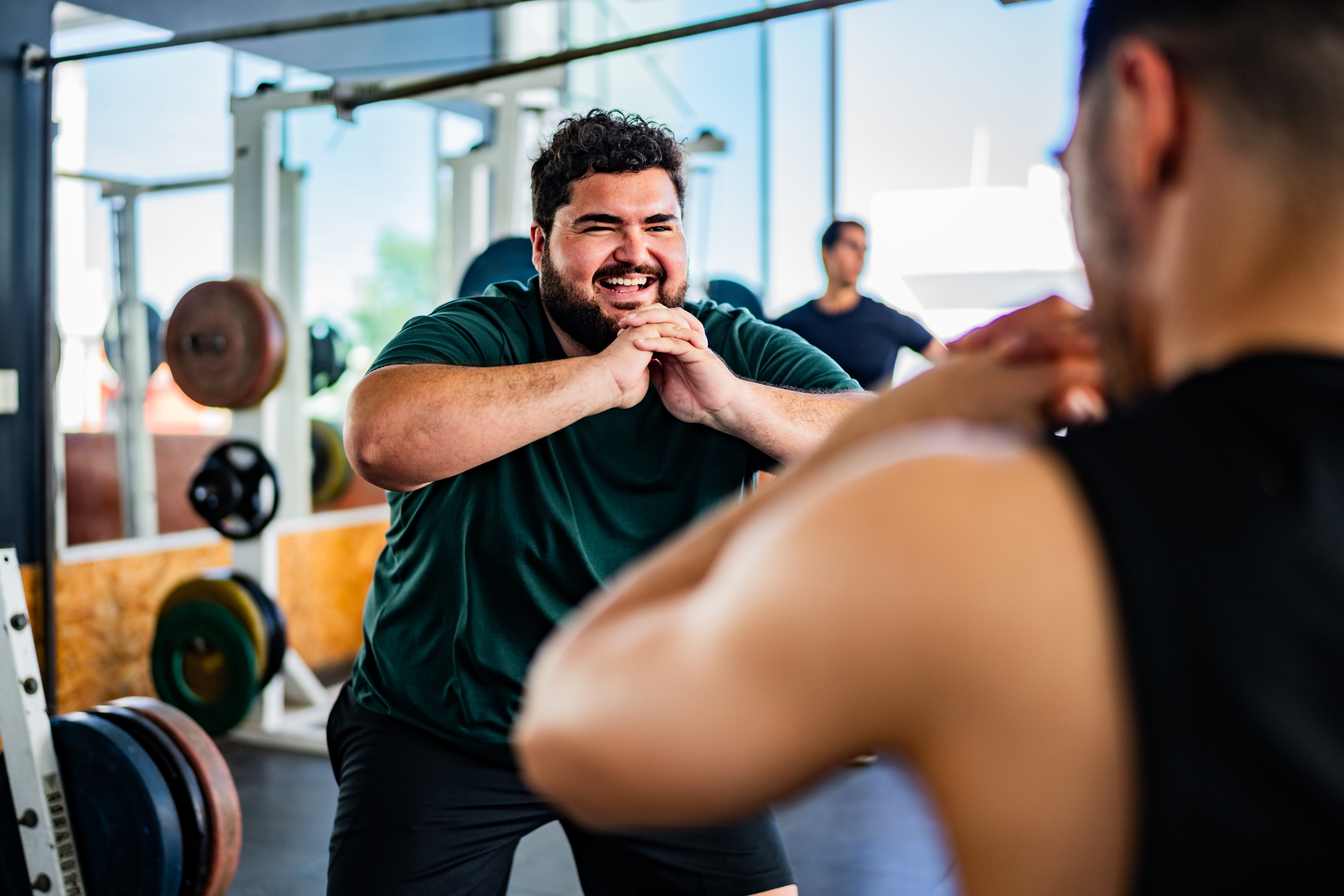 A man smiles as he works out in the gym with a personal trainer.