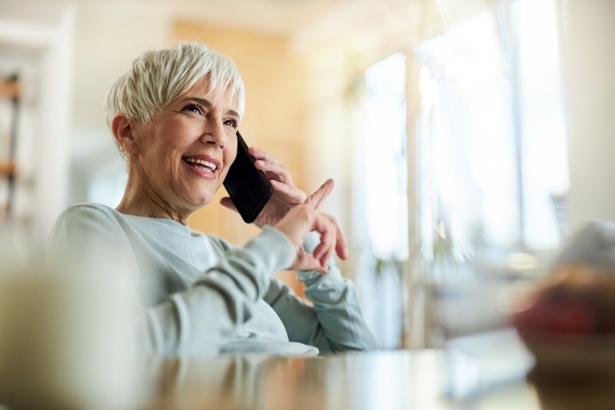 A woman talks on her smartphone while sitting at a table.