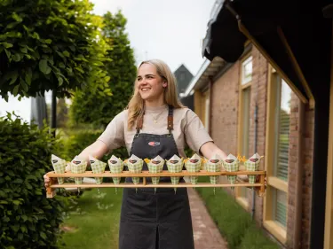 Persoon loopt met een stel puntzakken van Farm Frites