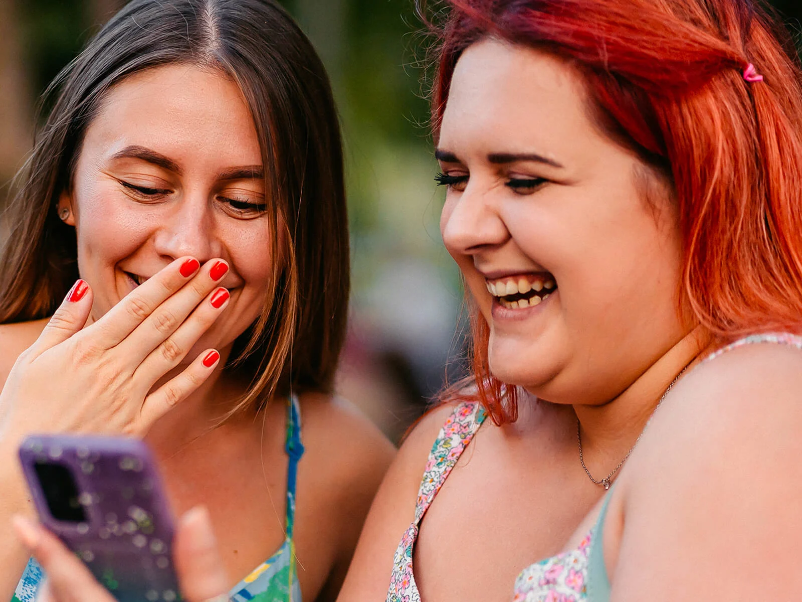 Two women looking at a smartphone and sharing a laugh, representing the freedom to stream, browse and stay connected with unlimited mobile data.