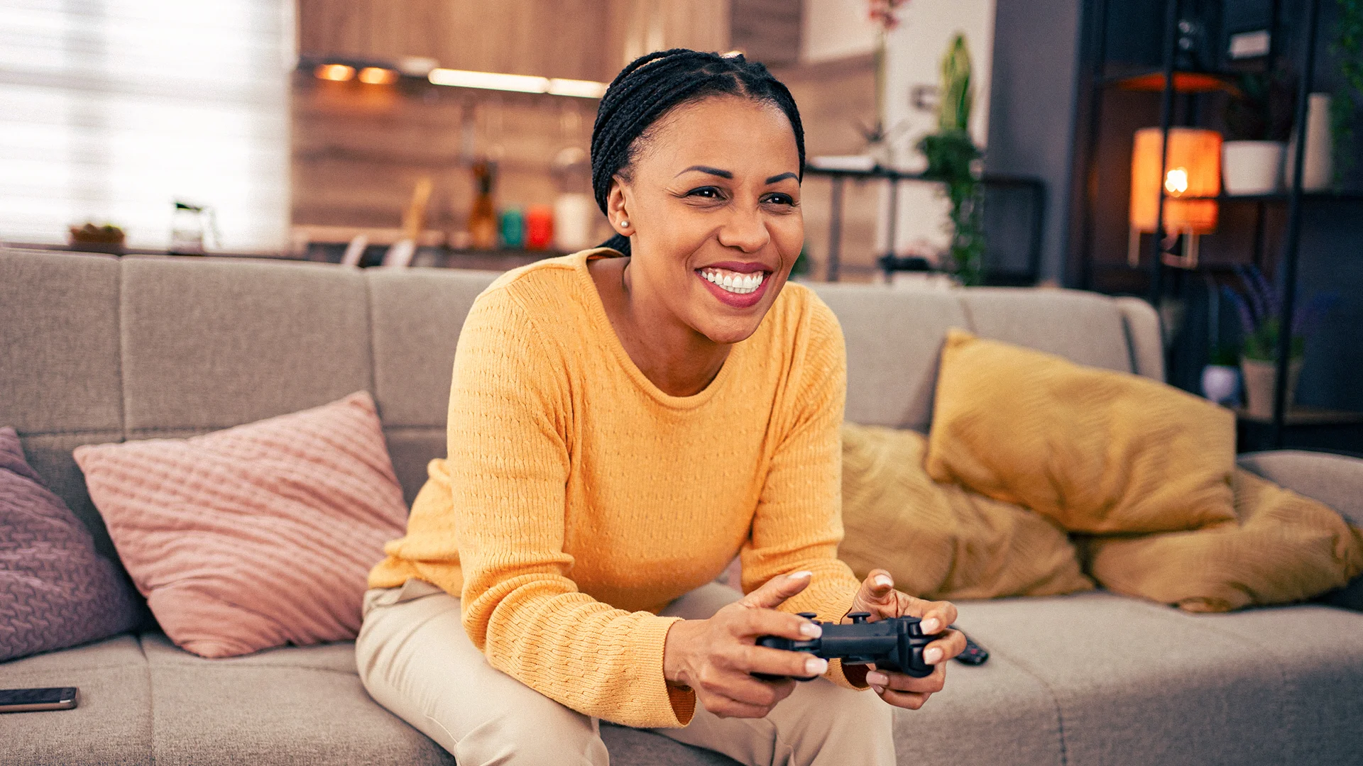 Woman relaxing on a sofa while playing a video game at home, representing the fast and reliable broadband needed for online gaming, streaming and entertainment.