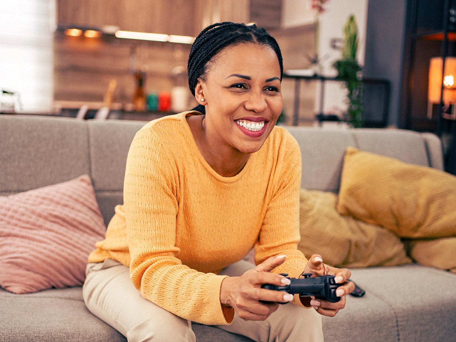 Woman relaxing on a sofa while playing a video game at home, representing the fast and reliable broadband needed for online gaming, streaming and entertainment.