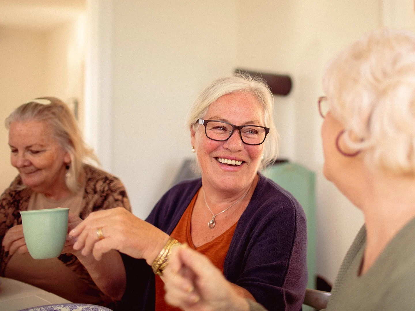 Friends enjoying a hot drink together at home, representing the comfort and peace of mind that comes from managing household energy costs effectively.