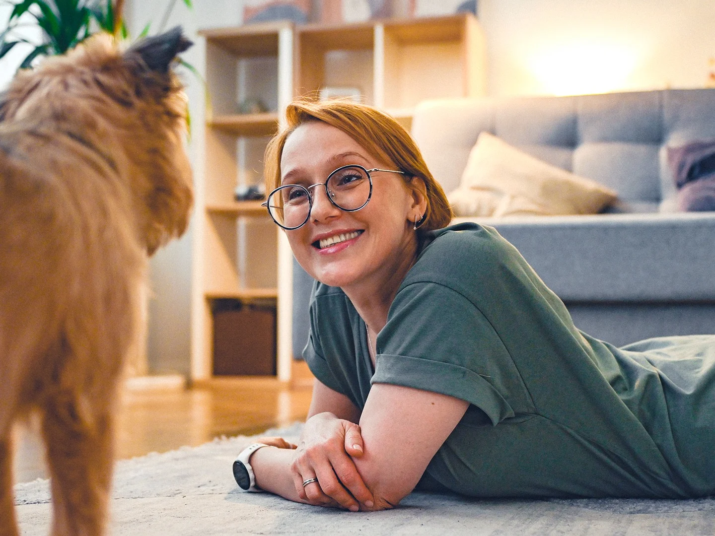 Woman relaxing on the floor with her dog in a comfortable living room, representing the peace of mind that comes with protecting your home and belongings.