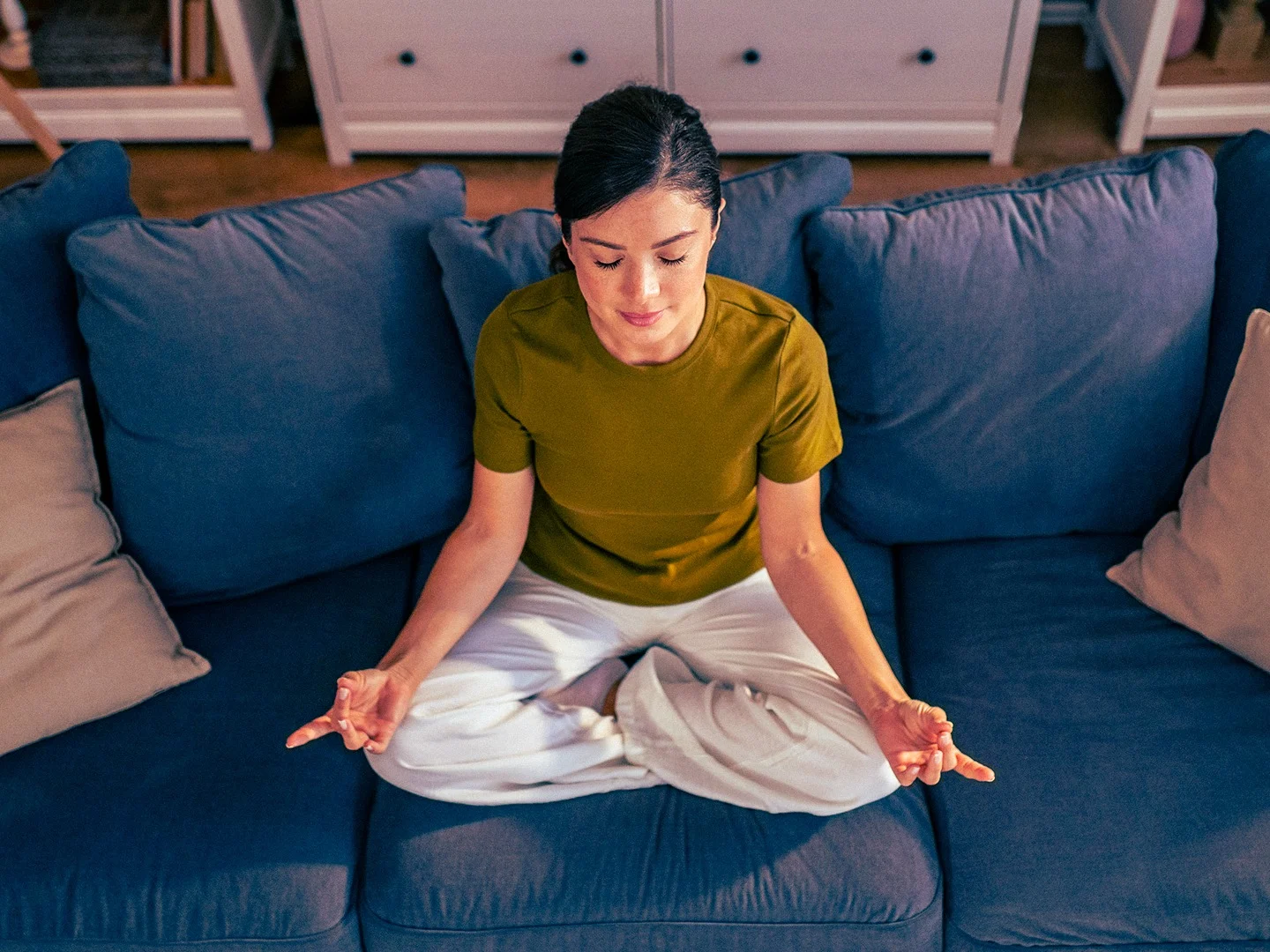 Woman sitting cross-legged on a sofa in her living room, representing the comfort and reassurance of protecting your belongings with contents insurance.