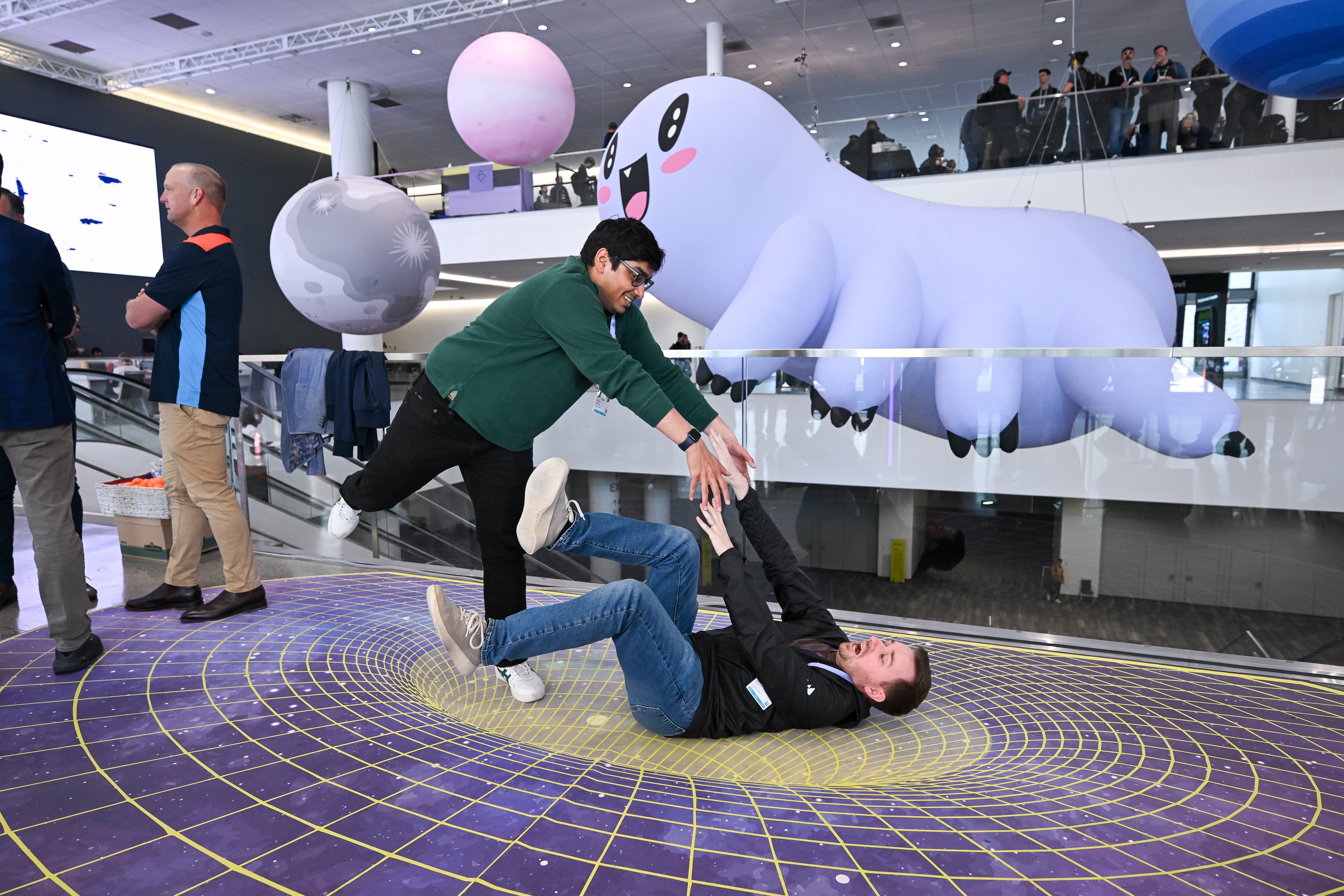 Replay 2026 attendees attempting partner yoga in front of inflatable Ziggy