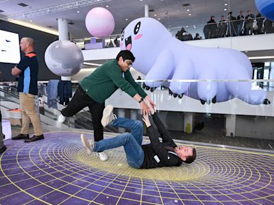 Replay 2026 attendees attempting partner yoga in front of inflatable Ziggy