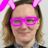 Person wearing pink bunny ears and purple glasses with black sweater and patterned collar against gray background