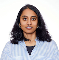 Professional headshot of a woman with long dark hair wearing a blue and white striped shirt against a white background.