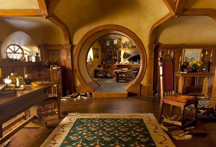 The interior of Bag End, a round doorway framing a hobbit kitchen with food laid out on the table and a fire in the hearth