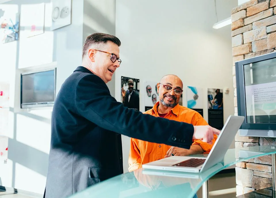 2 people pointing at computer