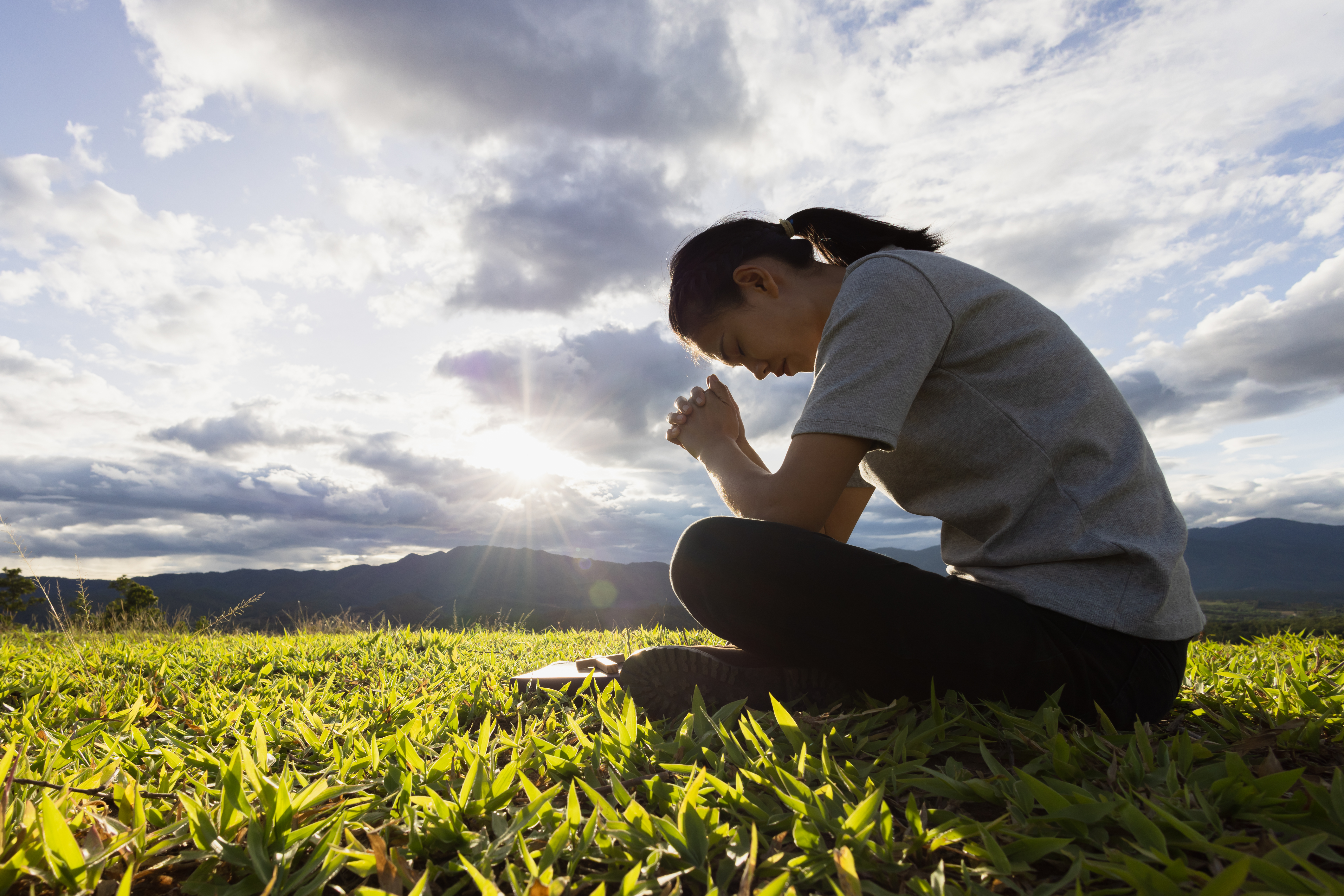 Woman Praying in Nature with Beautiful Mountainous Background