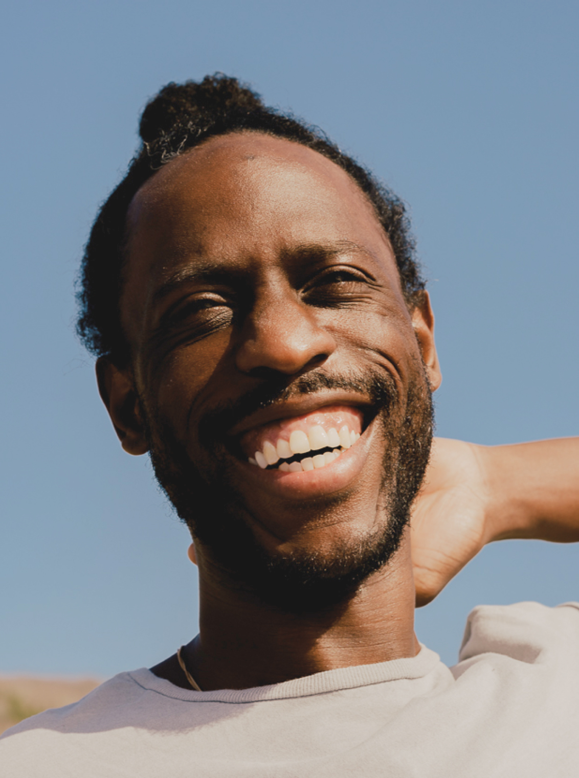 Photo of a man smiling in front of a blue sky