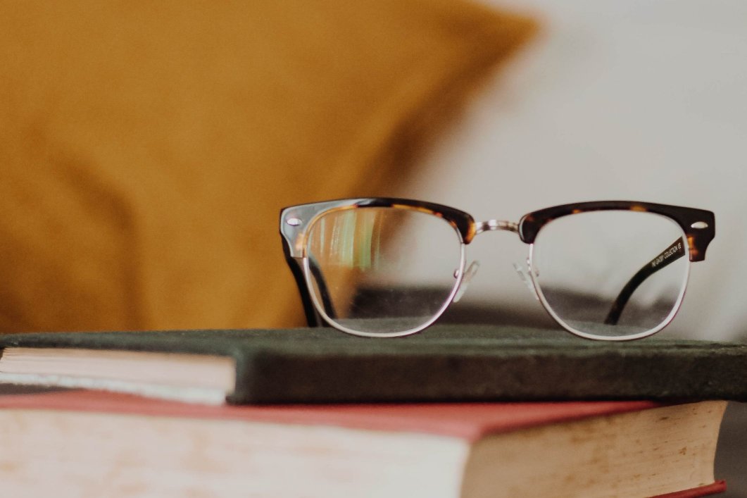 A pair of eyeglasses sitting on top of stacked books.