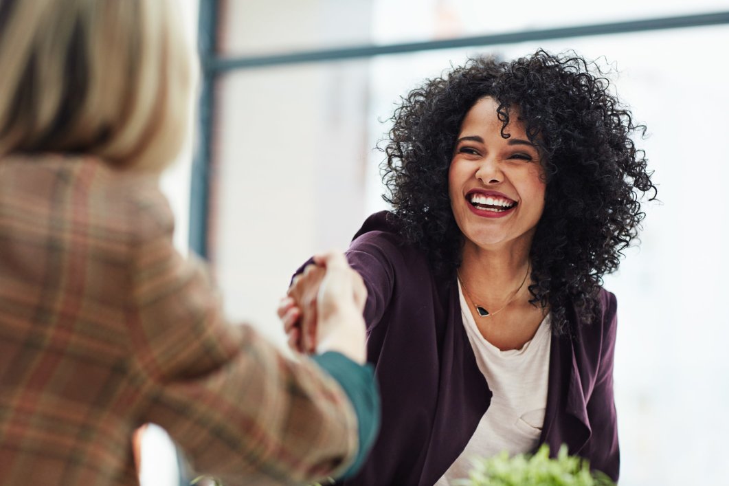 An employee benefits broker shaking the hand of her client.