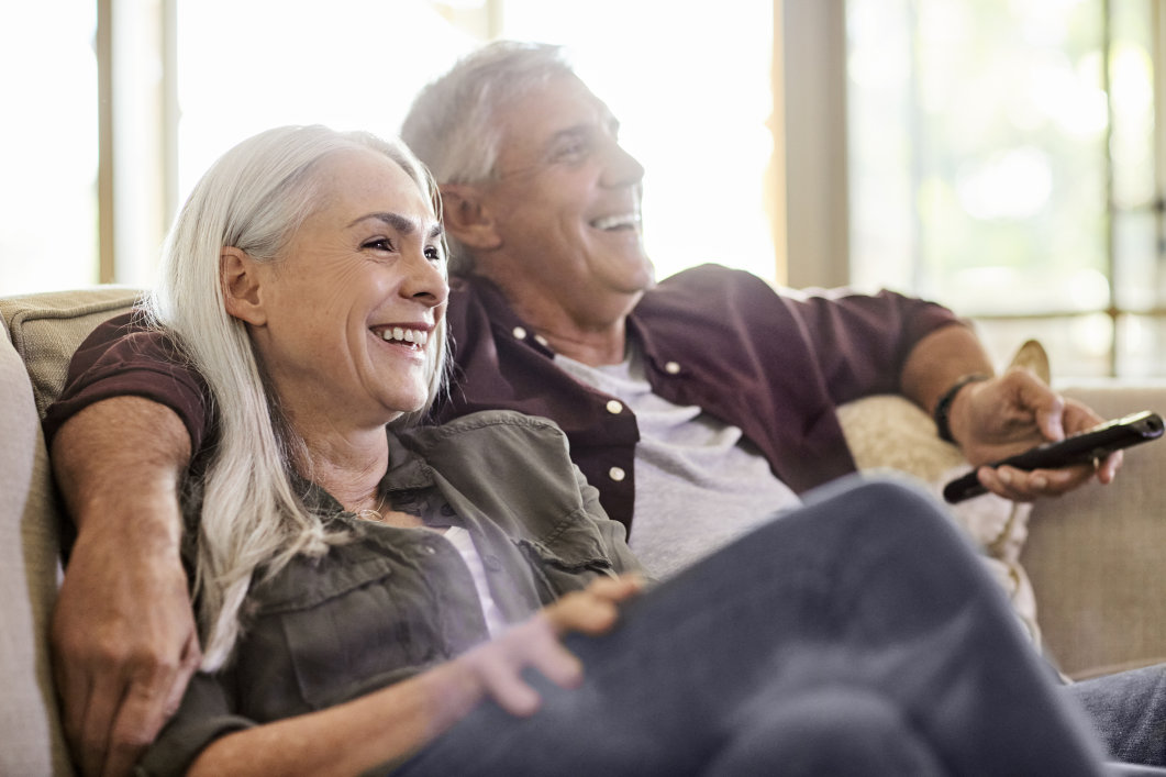 An older couple watching TV in their home