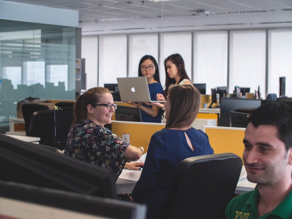 Colleagues talk with each other in an open office space.