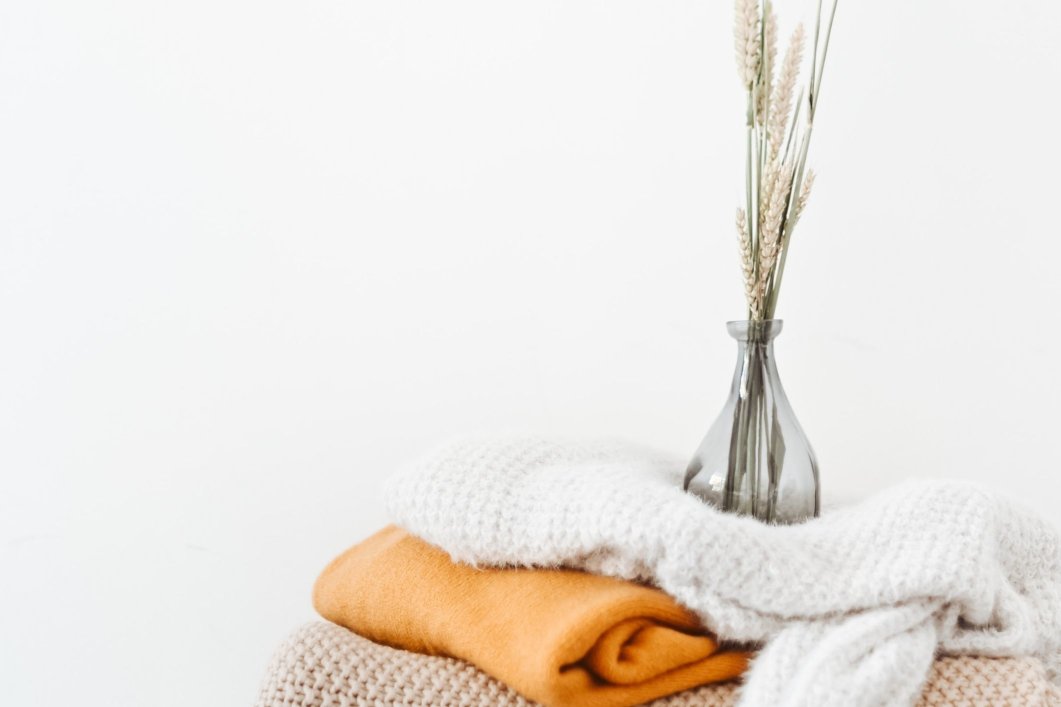 Flowers in a clear vase placed on top of stacked and folded blankets