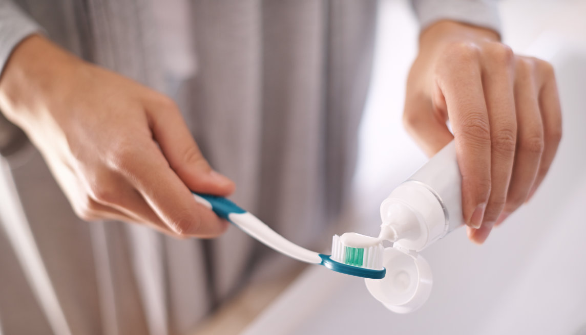 A person squeezing toothpaste onto their toothbrush.