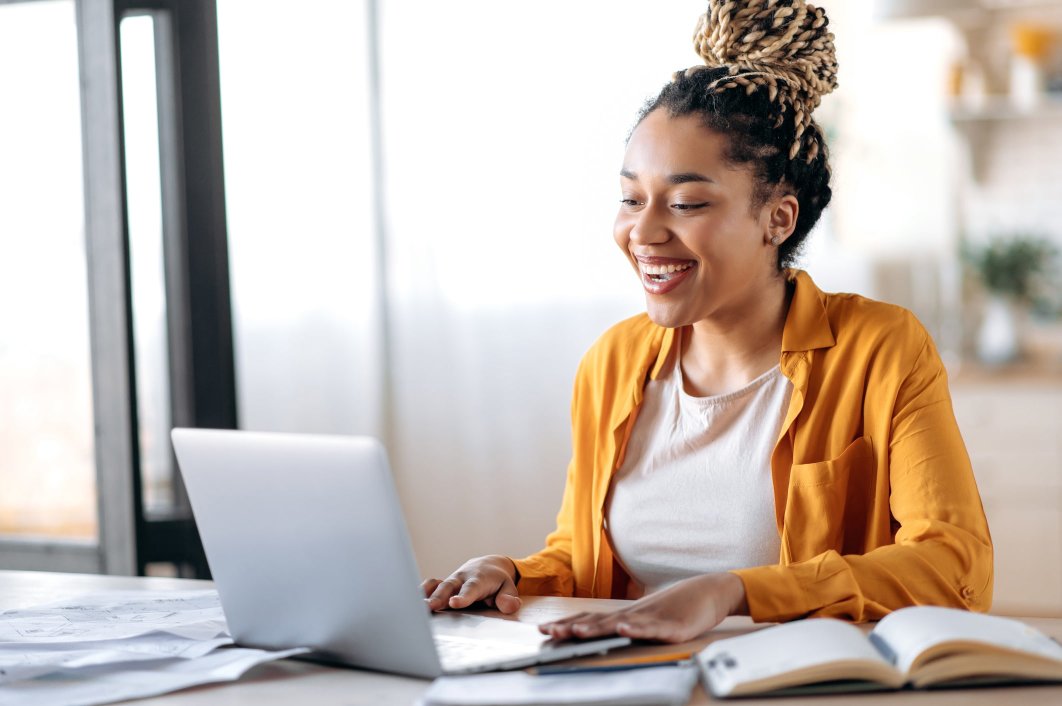 A young woman smiling while working from home on her laptop