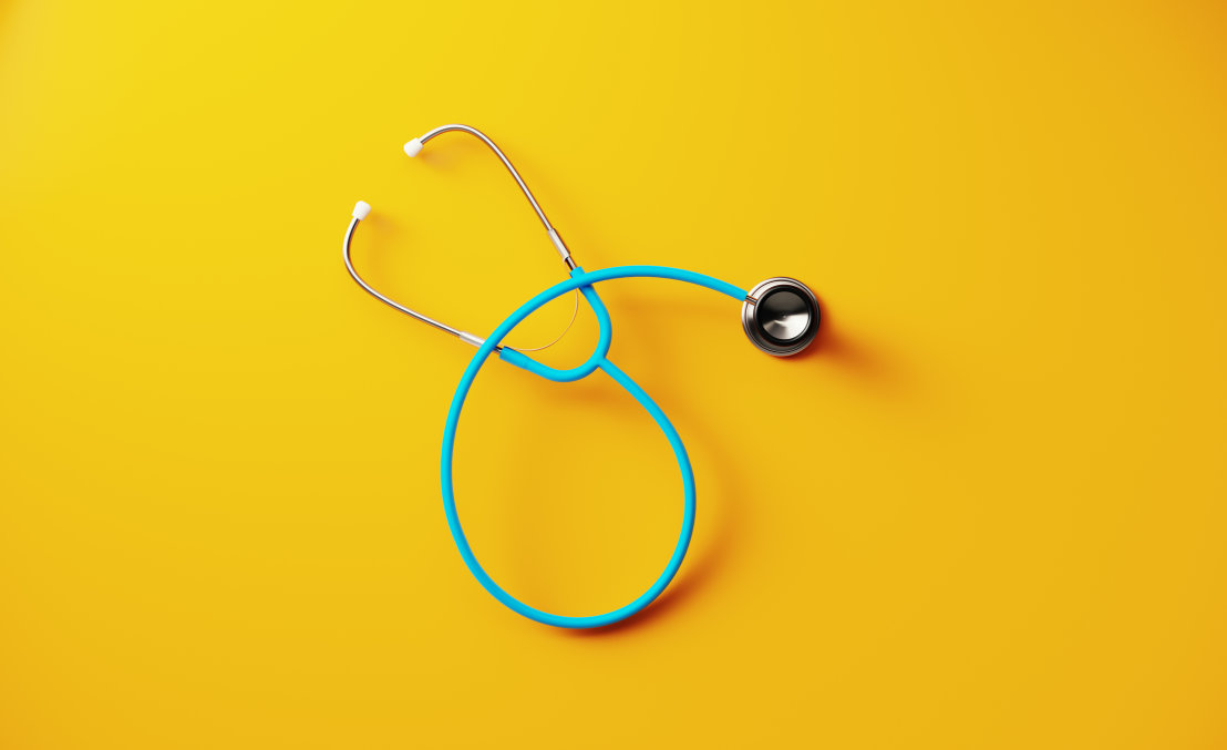 A stethoscope laying on a bright yellow background.