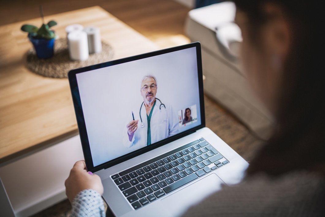 A person having a video chat with a doctor on their laptop during a telehealth appointment.