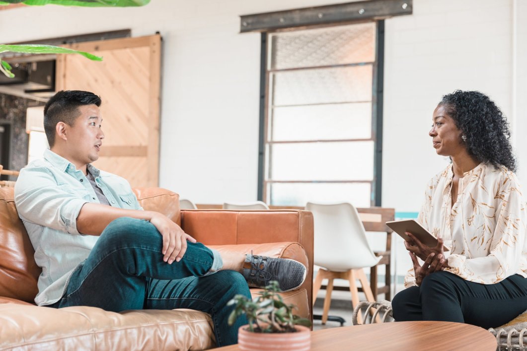 A male patient speaking with a female psychologist during a therapy session.