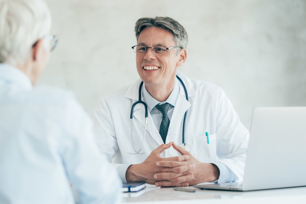 A male doctor speaking with a patient who has a point of service health plan