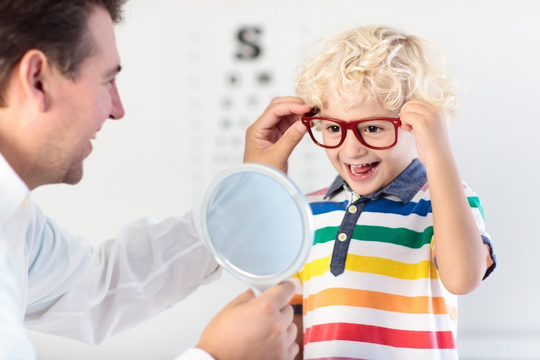 An eye doctor helping a toddler pick out glasses