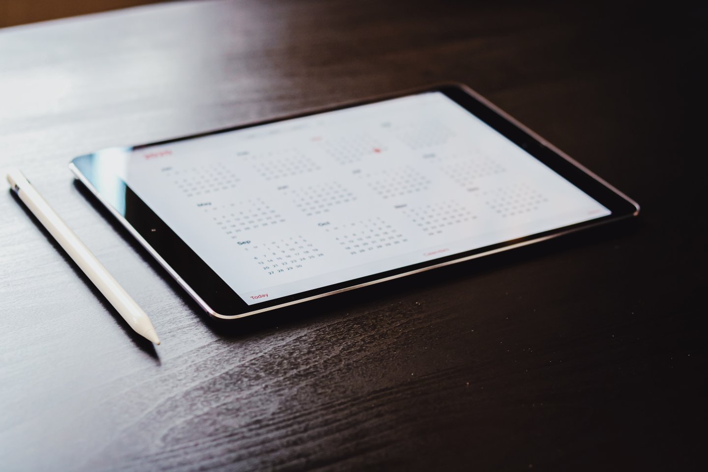 An iPad on a table with a calendar displayed on the screen