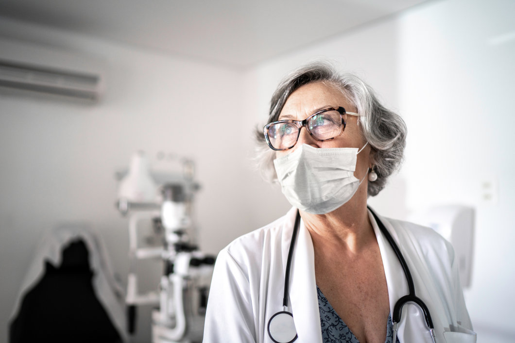 A female doctor looking into the distance while wearing a face mask