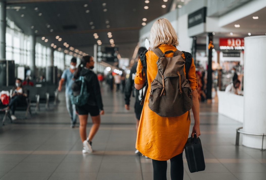 A woman with a backpack and a suitcase walking in an airport