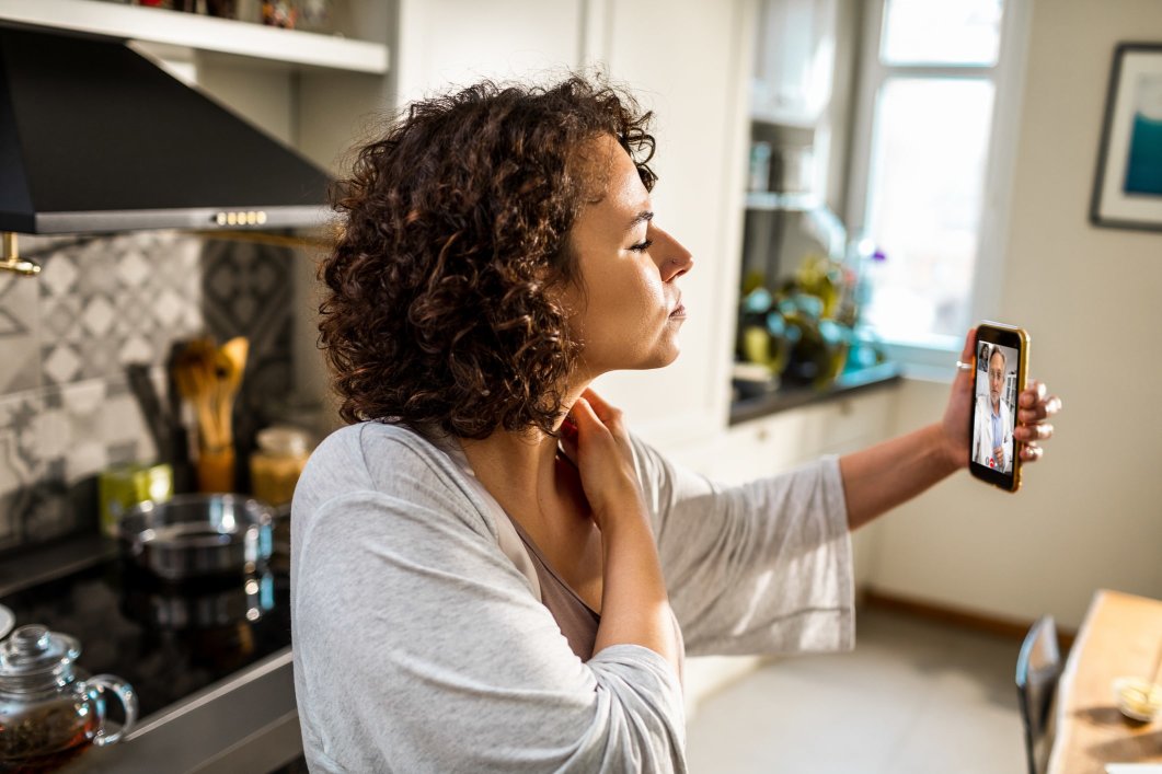 A woman speaking to her doctor on a video call during a telehealth appointment.