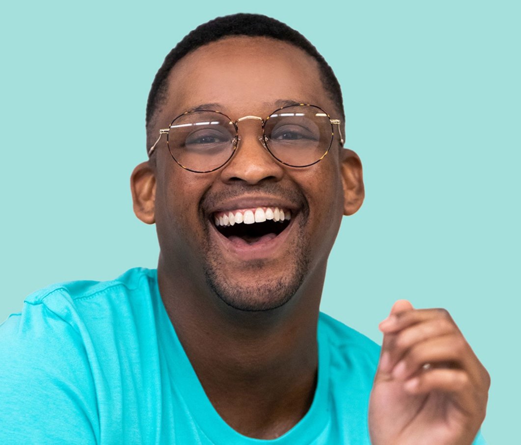 A man smiling at the camera while wearing glasses