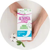 Un paquete de compresas Ausonia Cotton Protection Normal se coloca en las manos de una mujer. 