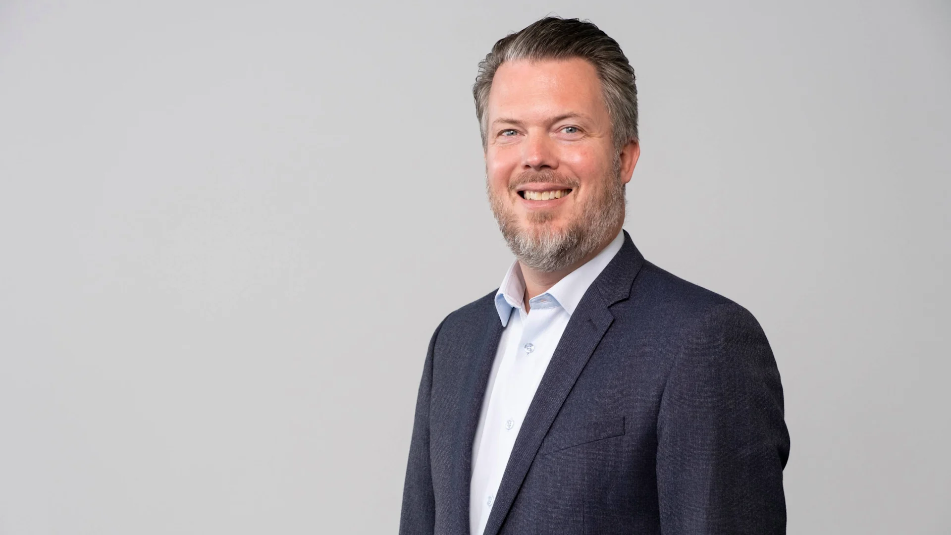Portraitfoto von Stefan Zuercher. Er trägt ein weisses Hemd ohne Krawatte und ein blauer Sakko.