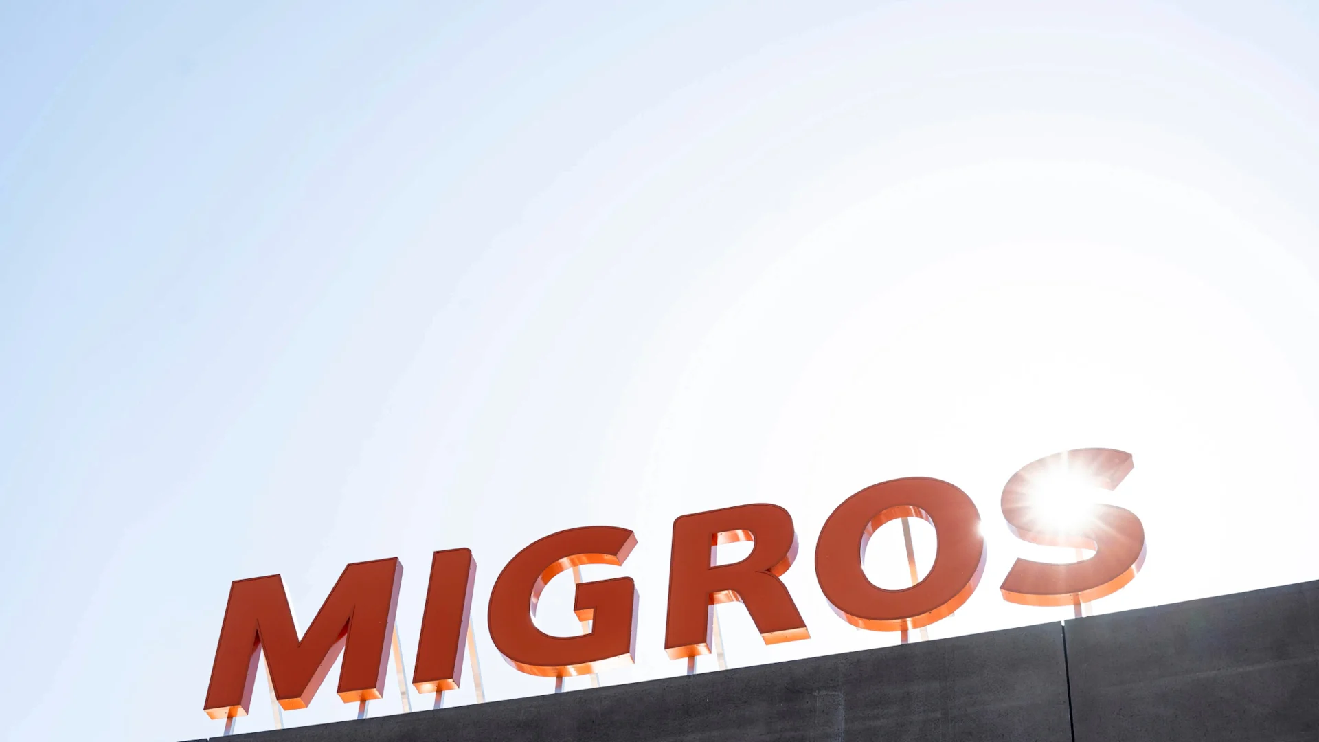 Inscription Migros sur un bâtiment en contre-jour