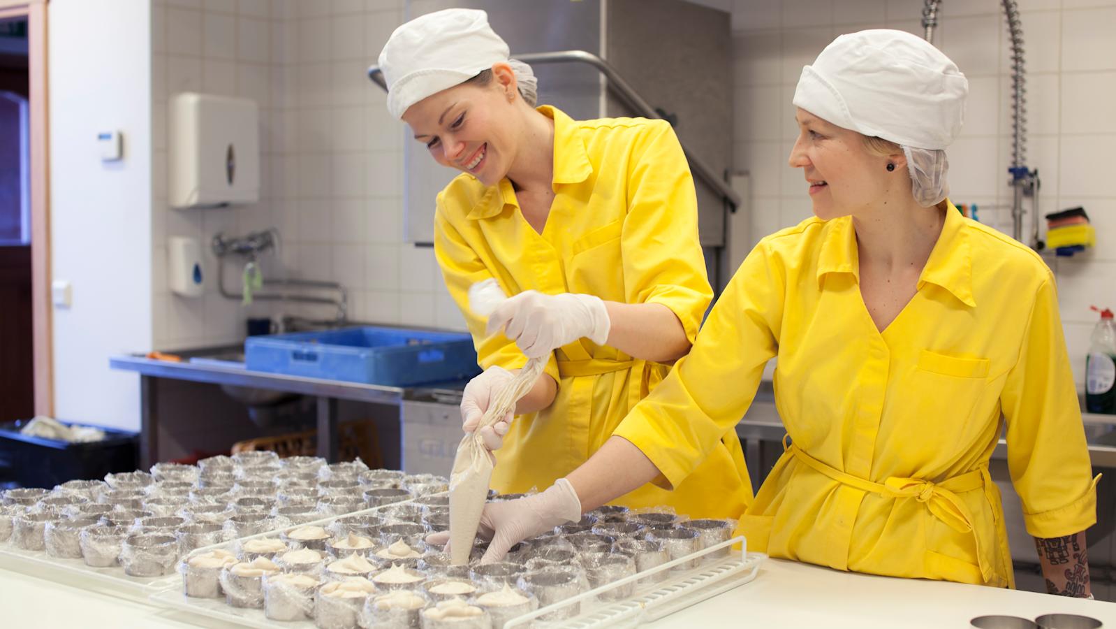 Matilda Mela (vas.) ja Kaisa-Leena Pesonen pursottavat massaa muotteihin.