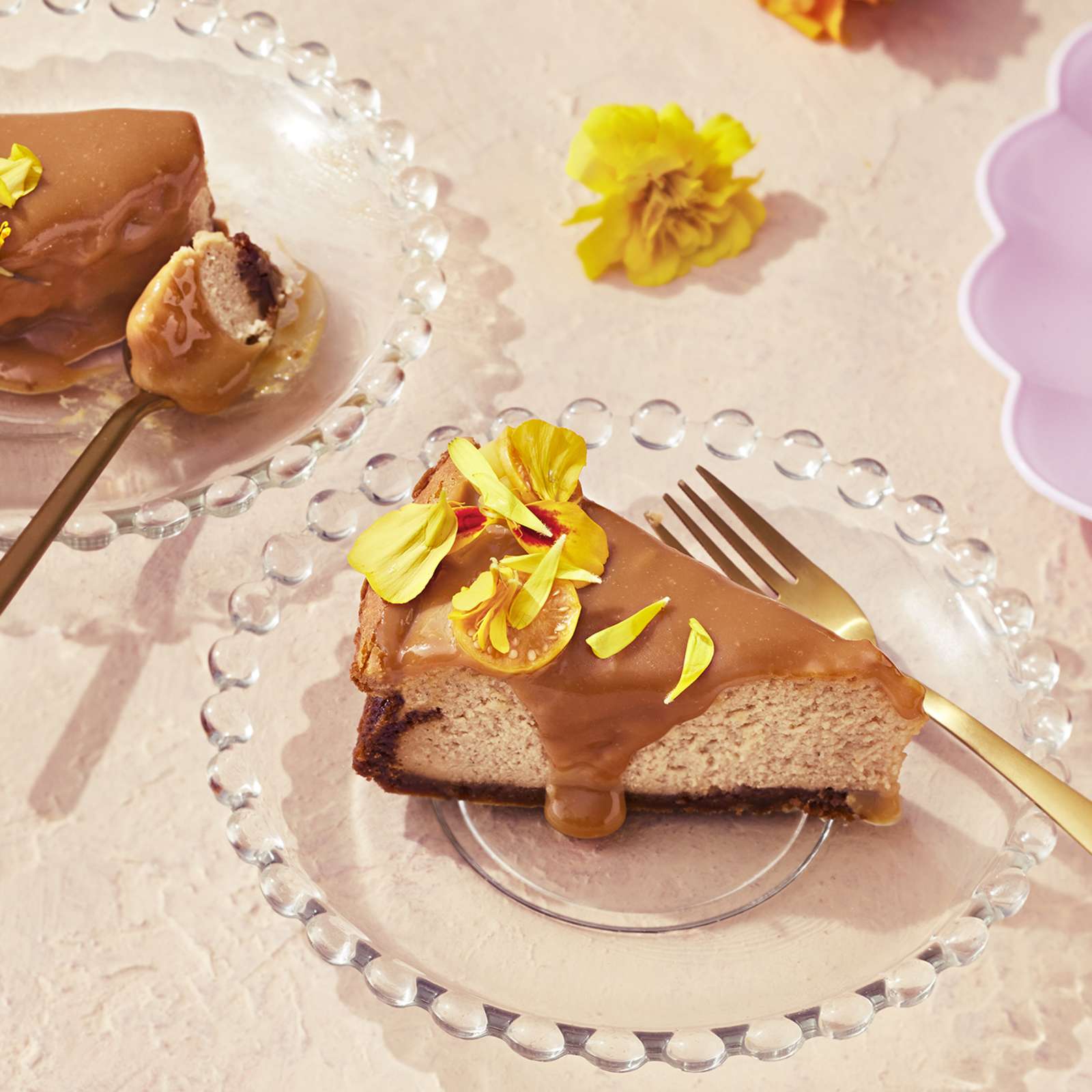 Suolakinuski-juustokakku, josta leikattu kaksi palaa lasisille lautasille. Kakkupalat koristeltu keltaisilla samettikukilla.