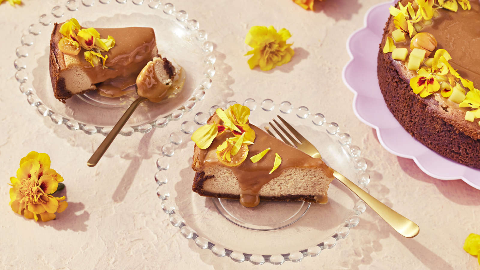 Suolakinuski-juustokakku, josta leikattu kaksi palaa lasisille lautasille. Kakkupalat koristeltu keltaisilla samettikukilla.