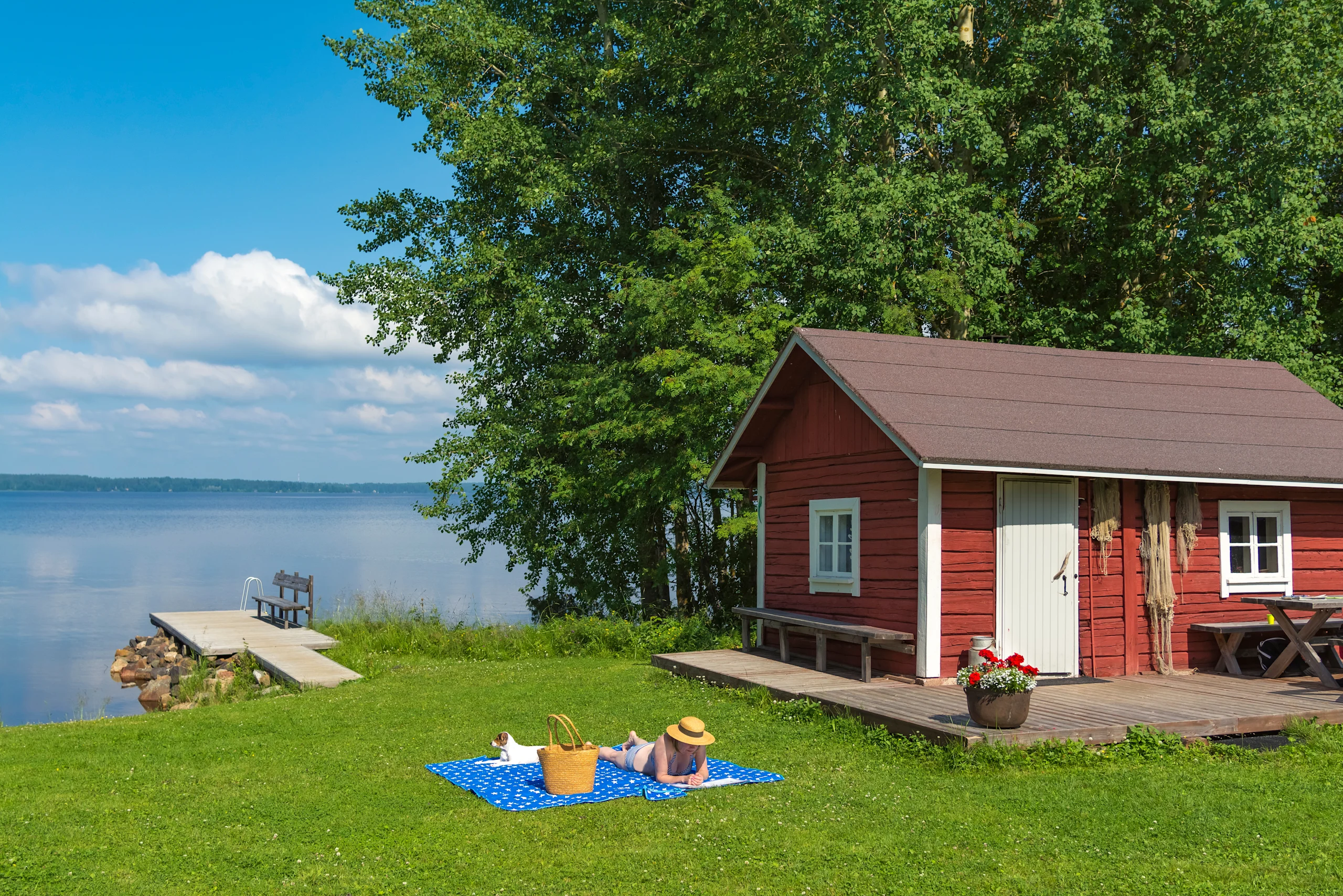 Nainen ottaa aurinkoa mökin rannassa