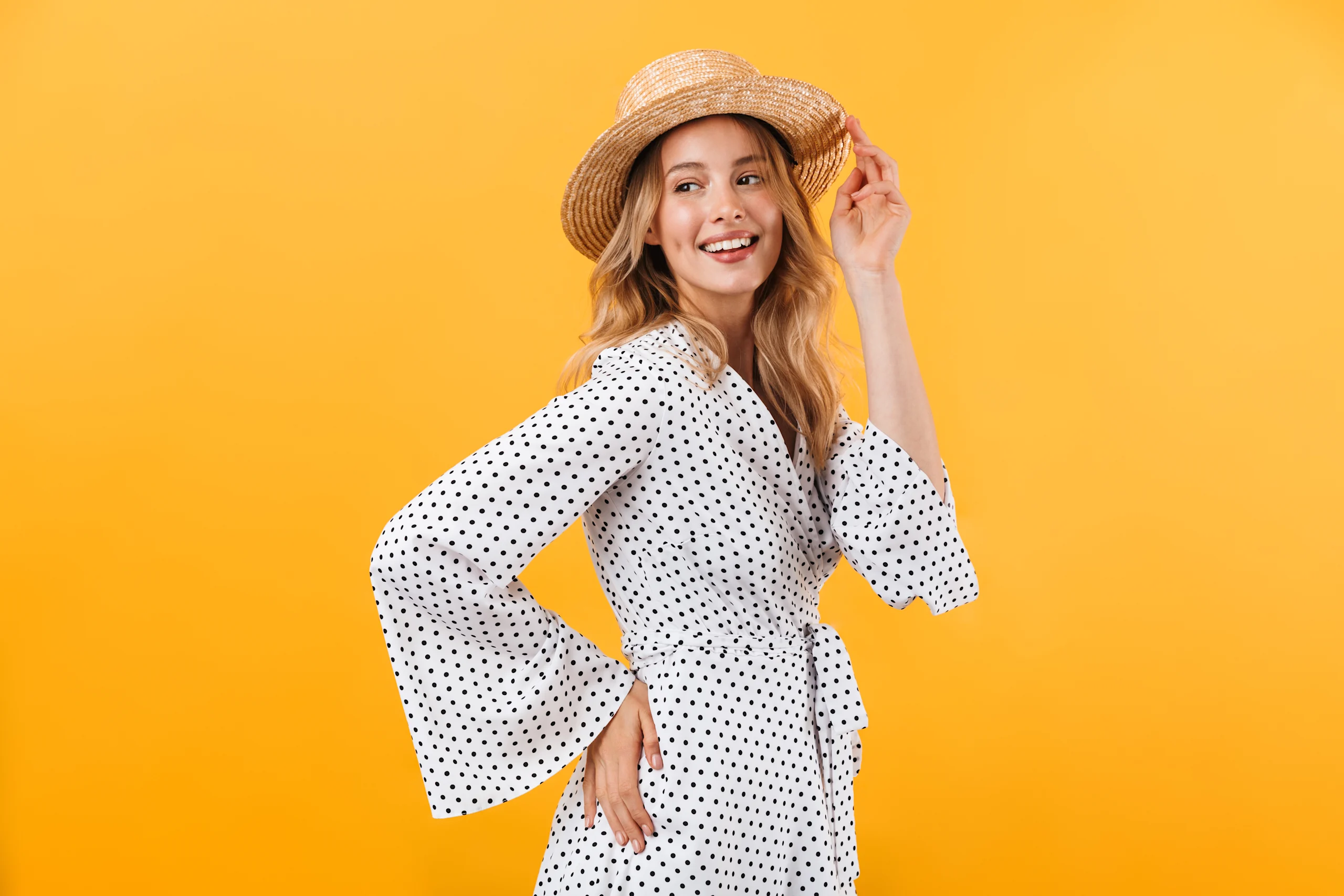 Nainen poseeraa kesämekossa keltaista taustaa vasten