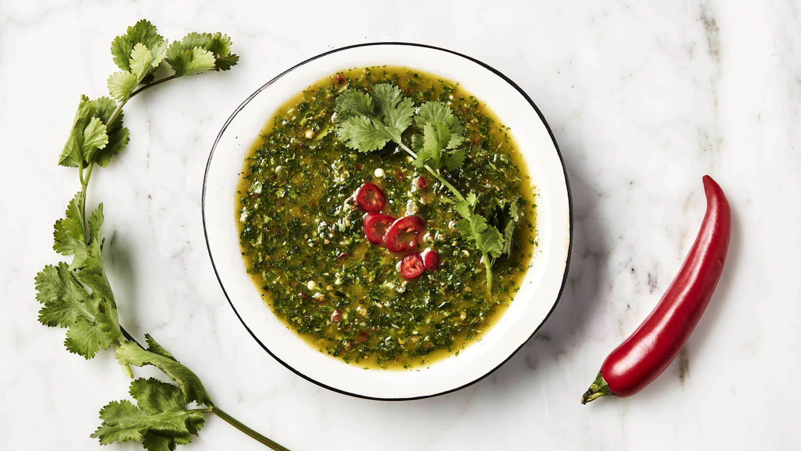 Chimichurri laakeassa kulhossa chiliviipaleilla ja korianterilla koristeltuna.