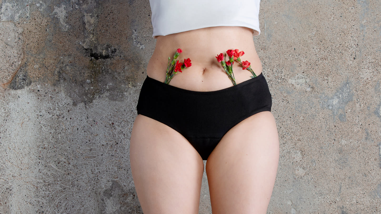 Libresse Intimawear cotton hipster kuukautisalushousut mallin päällä, somisteena punaisia neilikoita.