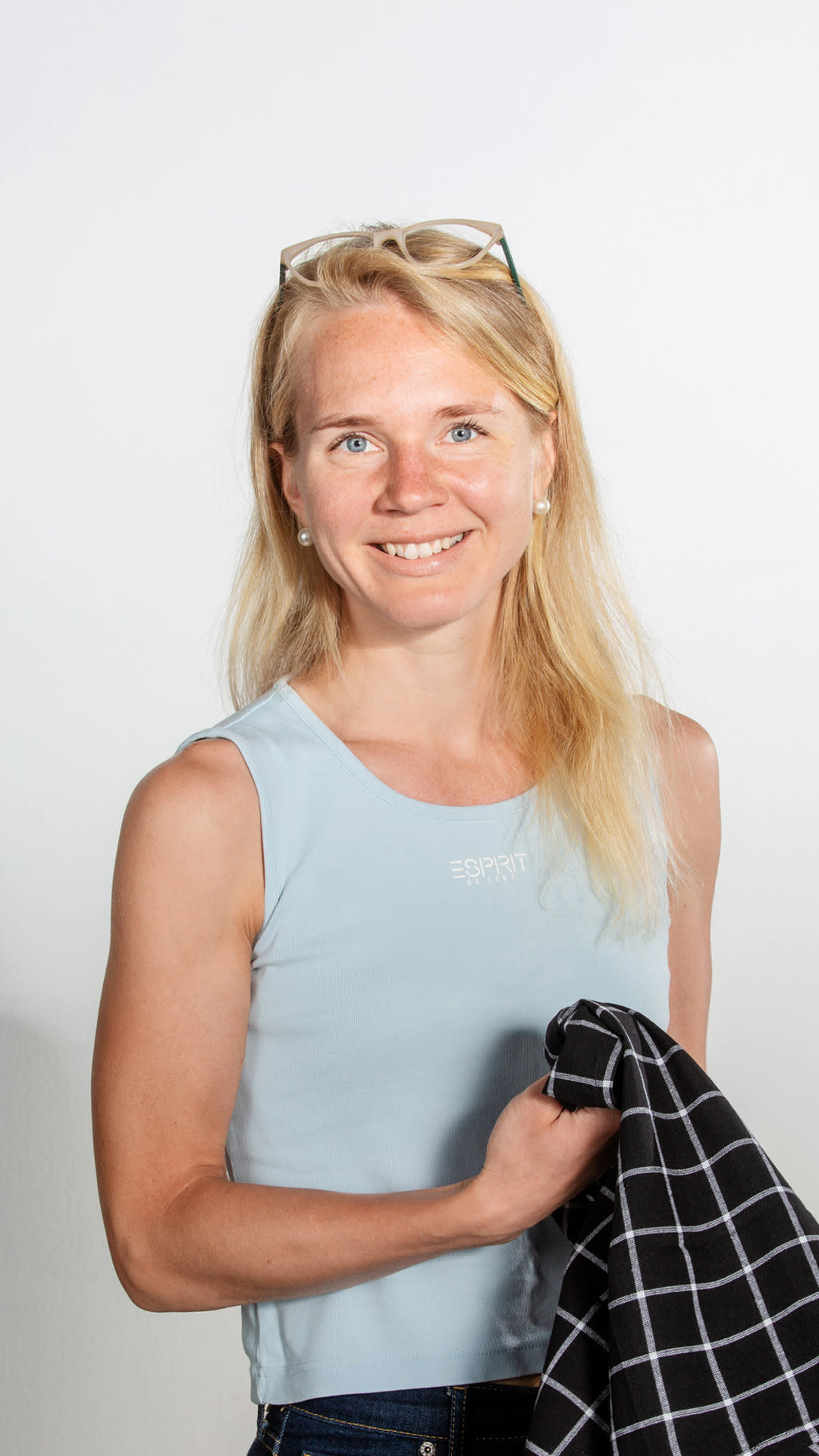 Ravitsemusterapeutti Aino niemi katsoo hymyillen kameraan keittiöpyyhe käsissään.
