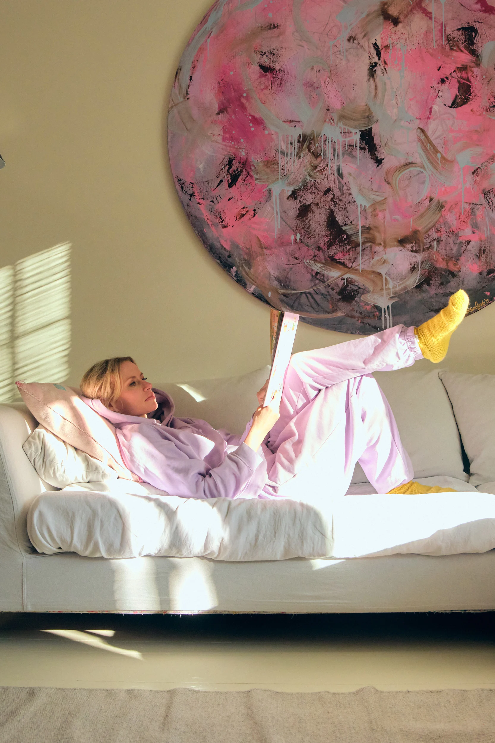 Minka Kuustonen makaa sohvallaan, taustalla pyöreä taideteos.