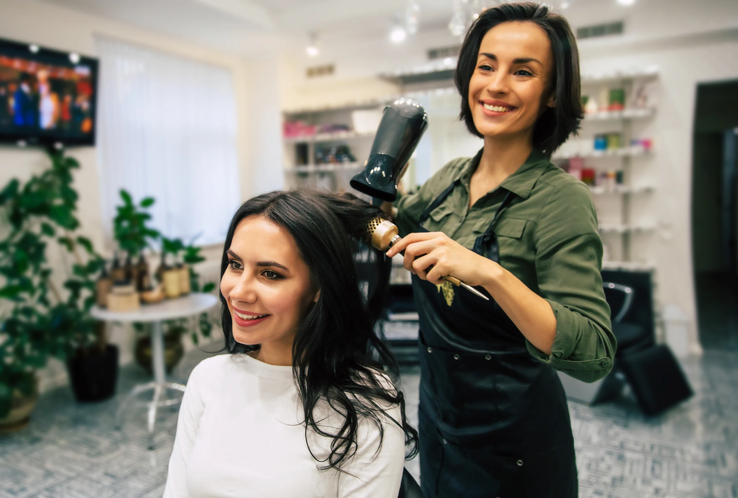 Kampaaja kuivaa asiakkaan hiuksia