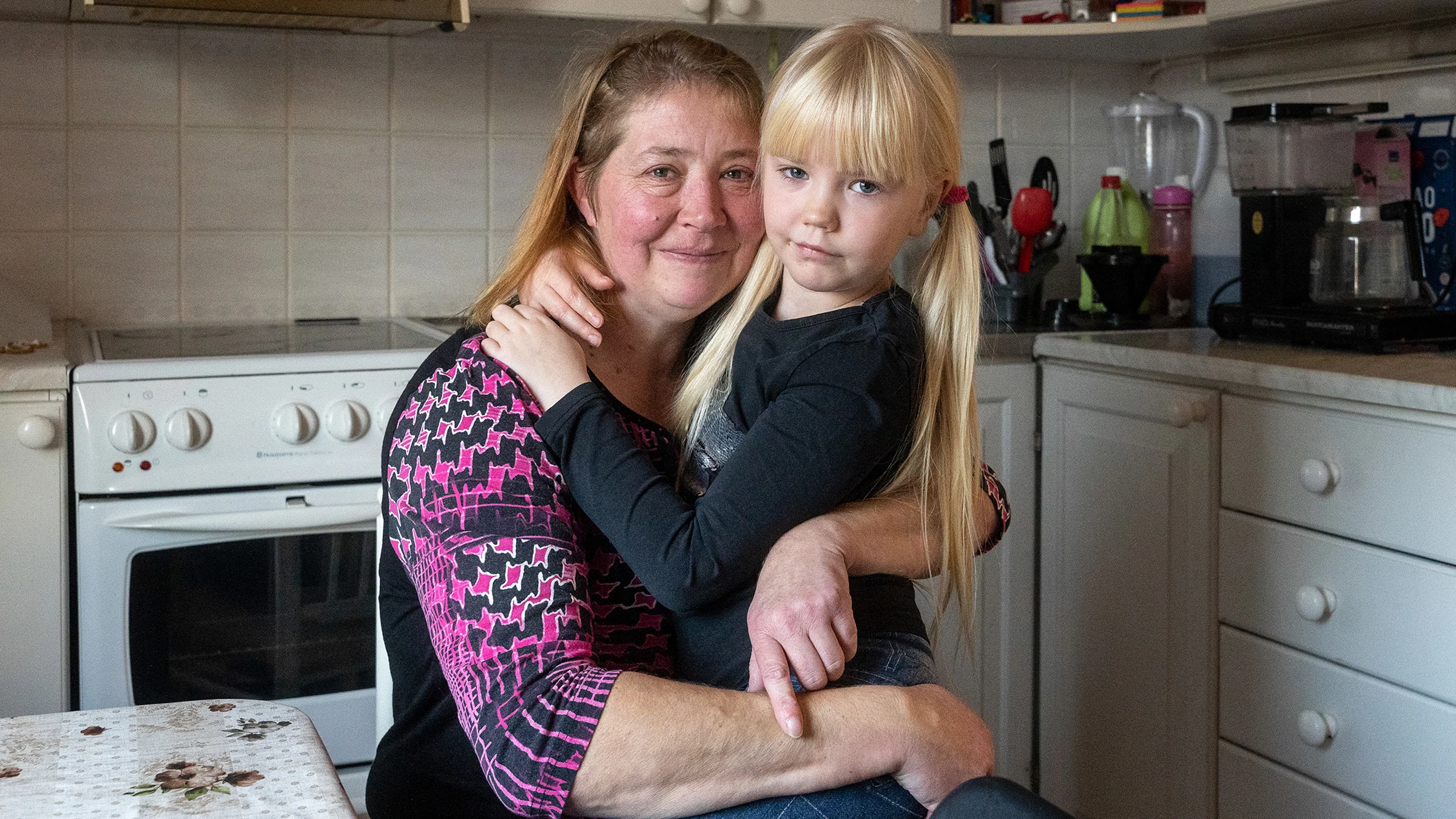Äiti Heidi Perttula ja tytär Elisa halaavat keittiössä.