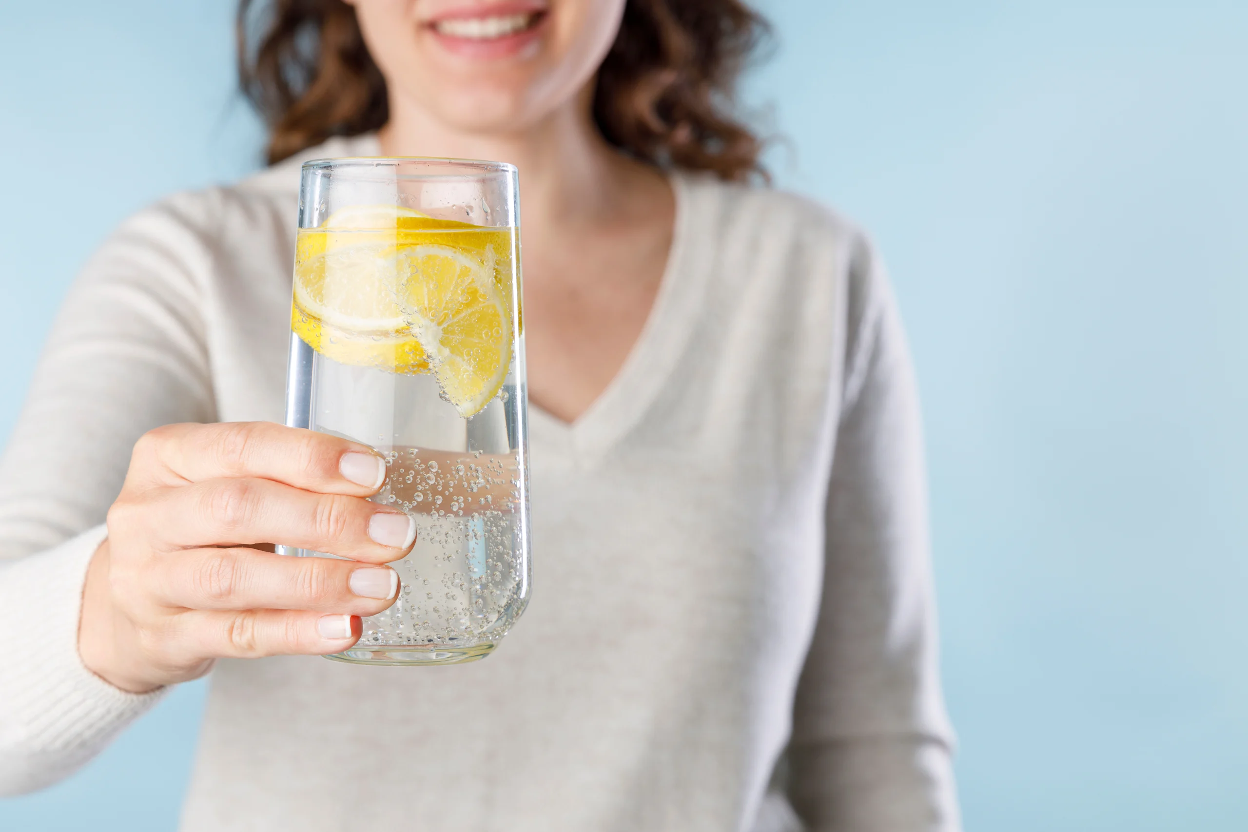 Nainen pitelee kädessään vesilasia